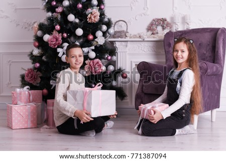 Happy boy and girl standing near the fireplace and a Christmas tree. Children waiting for the new year