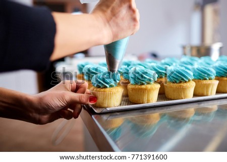 The confectioner's hands are decorated with a cream of pipping b Royalty-Free Stock Photo #771391600