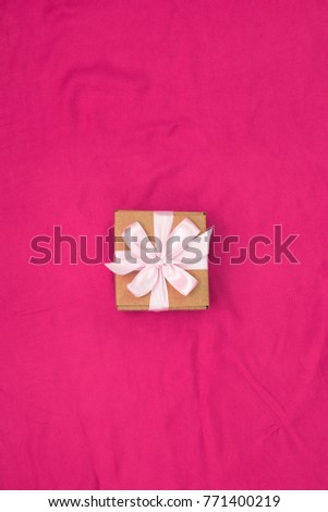 One gift box tied with satin coloured ribbon on a red background Gifts in boxes for the holiday. Top view flat lay