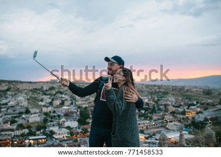 A beautiful couple doing selfie at sunset against the backdrop of the city of Goreme in Cappadocia in Turkey.