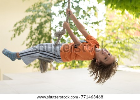 Cute happy little boy upside down on swing rope Royalty-Free Stock Photo #771463468