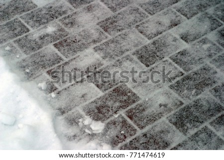 Tiled pavement covered with white snow. Winter background