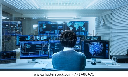 In the System Control Data Center Technician Operates Multiple Screens with Neural Network and Data Mining Activities. Room is Light and Full of Monitors with Working Neural Network on Them. Royalty-Free Stock Photo #771480475