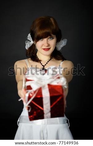 Young attractive woman gives a gift in red box