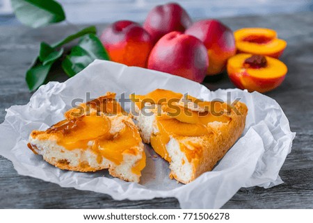 A pie with nectarines on a gray wooden table. Soft focus.