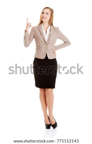 Beautiful caucasian business woman is pointing up.