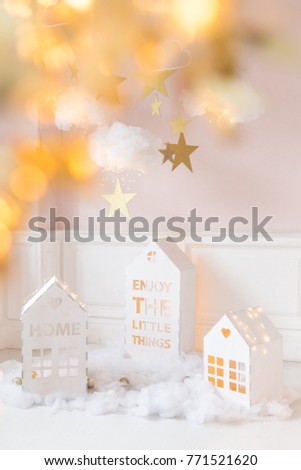 Christmas background. Christmas card. Toy wooden white houses with lights. Clouds of cotton wool with light. Star gold color. Cozy photo zone for a photo shoot. Children's room decoration.