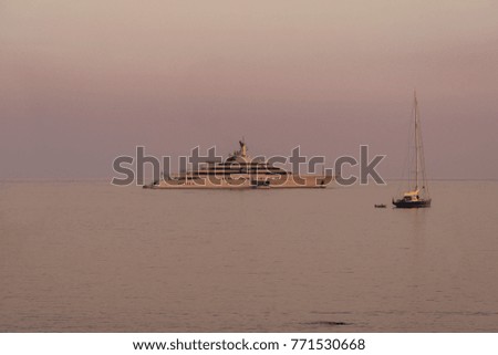 The boat is anchored at sea at sunset, in the twilight. Beside her sailboat. All in soft pink colors.