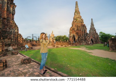 Young asian girl taking smartphone photo with mobile phone at Wat Chaiwatthanaram temple in Ayutthaya.