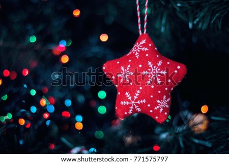Decorated Christmas tree closeup. New Year baubles macro photo with bokeh. Winter holiday light decoration. Soft toy in the form of a red star with patterns.