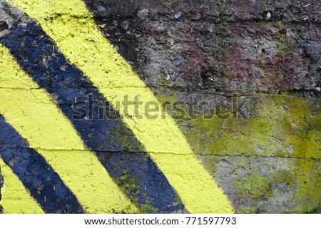 Old concrete wall texture with yellow and black stripes. Urban grunge background concept. 