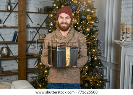 Donation gift on new year's Eve house party guy smiling at Christmas bearded guy in red hat