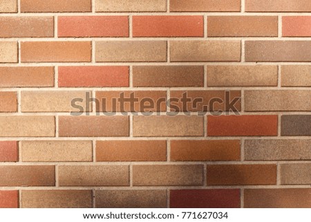 Multicolor brick wall background with light casting shadows on facing surface