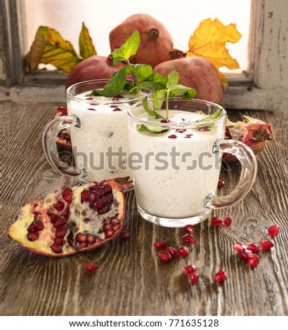 Rustic fruit still life concept with tasty healthy fresh dessert with two glass cup of yogurt and red pomegranate on the wooden background and old window.