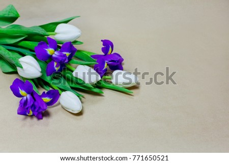 Bouquet of blue irises and white tulips closeup on the Kraft paper, shallow depth of field, selective focus, natural background.