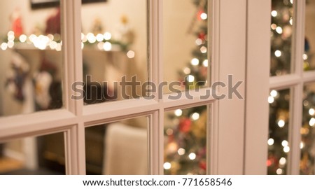Christmas tree and fireplace mantle through a window.  Shallow depth of field so tree and chimney mantle are out of focus.  