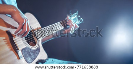 the hand of man playing acoustic guitar, close-up, flash of light, a beautiful light in the background with copy space
