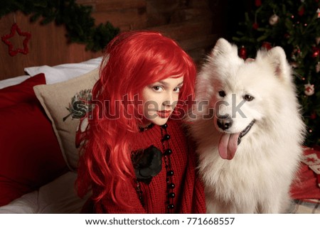 Winter dog holiday and Christmas. A girl in a knitted sweater and with red hair with a pet in the studio. Christmas woman with a beautiful face and pet.