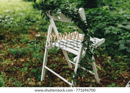 White folding chair with sign standing in heavy foliage