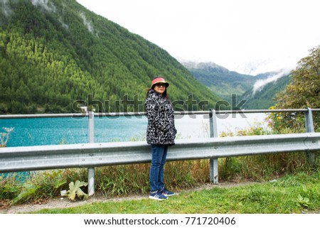 Traveler asian thai old woman travel and posing for take photo at Apls mountain and Fedaia Lake is a lake in Trentino-Alto Adige and the Province of Belluno, Italy.