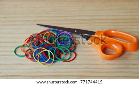 Colorful rubber bands and scissors on wooden table.