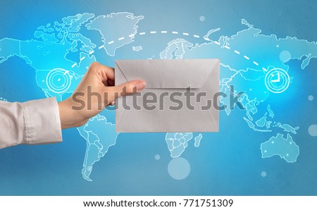 Female hand holding coloured and white envelope with blue map on the background
