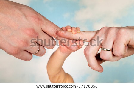 Thee hands of a baby and his parents with wedding rings Royalty-Free Stock Photo #77178856
