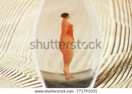 Tiny woman or girl in a glass box. Body issues concept or unrealistic standards of beauty. Depicted in miniature with Instagram filters and soft focus. Eating disorders, body dysmorphia.  Royalty-Free Stock Photo #771791035