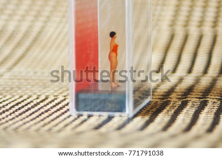 Tiny woman or girl in a glass box. Body issues concept or unrealistic standards of beauty. Depicted in miniature with Instagram filters and soft focus. Eating disorders, body dysmorphia.  Royalty-Free Stock Photo #771791038