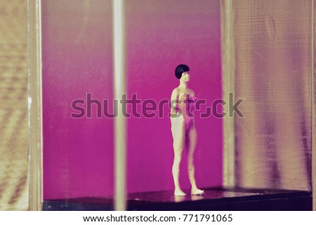Tiny woman or girl in a glass box. Body issues concept or unrealistic standards of beauty. Depicted in miniature with Instagram filters and soft focus. Eating disorders, body dysmorphia.  Royalty-Free Stock Photo #771791065