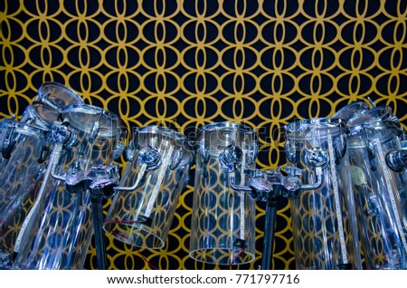 Adaptation modern drum made from different high glass for musical notes.
Musical instrument in front of pattern wall background.