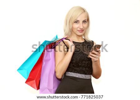 Beautiful young girl with shopping bags from clothes store, holding a mobile phone. Isolated on white background