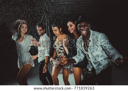 Group of friends dancing under the rain - Multiethnic people having party