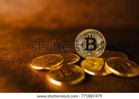 Many gold bitcoins laying on leather surface with a single bitcoin in sharp focus floating above them mining or blockchain technology for cryptocurrency
