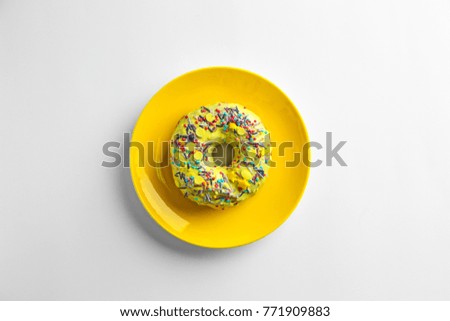 Yellow plate with tasty donut on white background