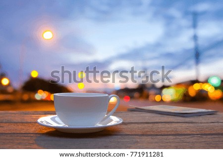 A front selective focus picture of a cup of coffee on wooden floor and blurred  light background 