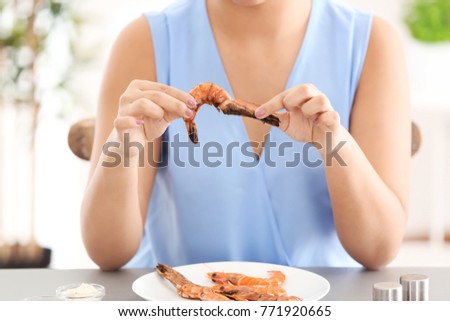 Young woman holding shrimp at table