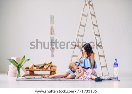 Funny little girl having fun with her mom in the white decorated room.
