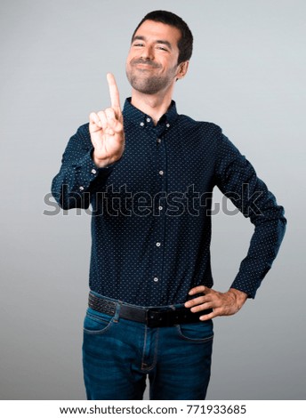 Handsome man counting one on grey background