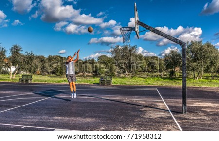 Lefty basketball player jump shot in a playground under clouds