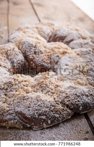 Big crispy sweet kringle with butter crumbs and powdered white sugar on wooden table top. homemade dessert with a tasty and heartwarming look for 8th of march, womans day.