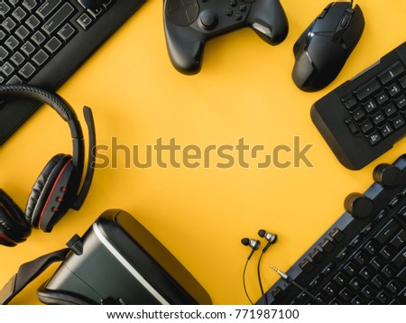 Gamer workspace concept, top view a gaming gear, mouse, keyboard, joystick, headset, VR Headset on yellow table background with copy space
