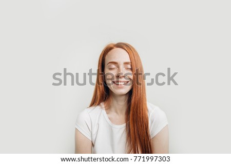 Beautiful ginger girl smiling posing with closed eyes.