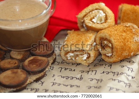 Cup of latte or cappuccino with cake roll on wooden desk