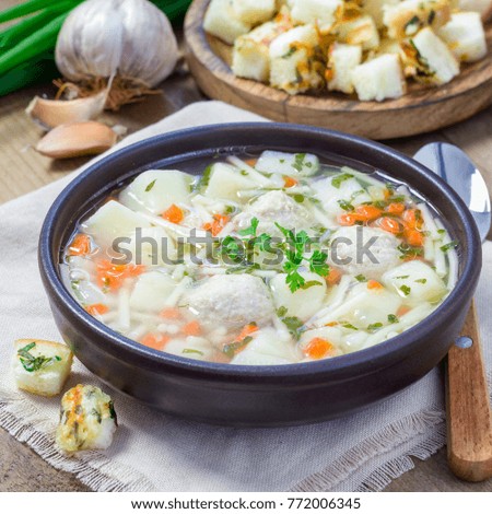 Homemade soup with meatballs and vegetables, served with cheese garlic parsley croutons, square format