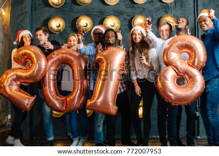 Group of colleagues having fun at new year celebration. people holding golden number balloons, 2018 year symbol