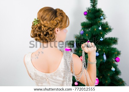 Girl with bright make-up Christmas. Redheaded girl with new-year decorations in a hair-do. Beautiful New Year and Christmas Tree Holiday Hairstyle and Make up.