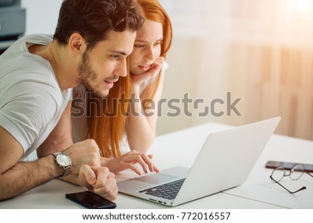 young Couple Using Laptop On Desk At Home and think Royalty-Free Stock Photo #772016557