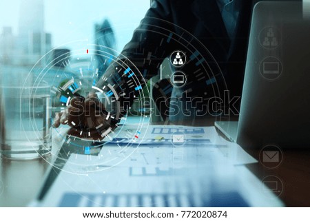 Hands of businessman using mobile phone in modern office with laptop and digital tablet computer in finance team meeting with VR icon diagram