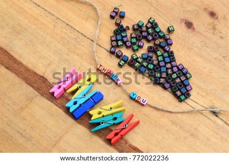 Creative layout of flat lay, made of multi color or colorful of wooden clips and beads with word 'Thank You' on wooden background. Selective focus. Appreciation, successful and gift concept.